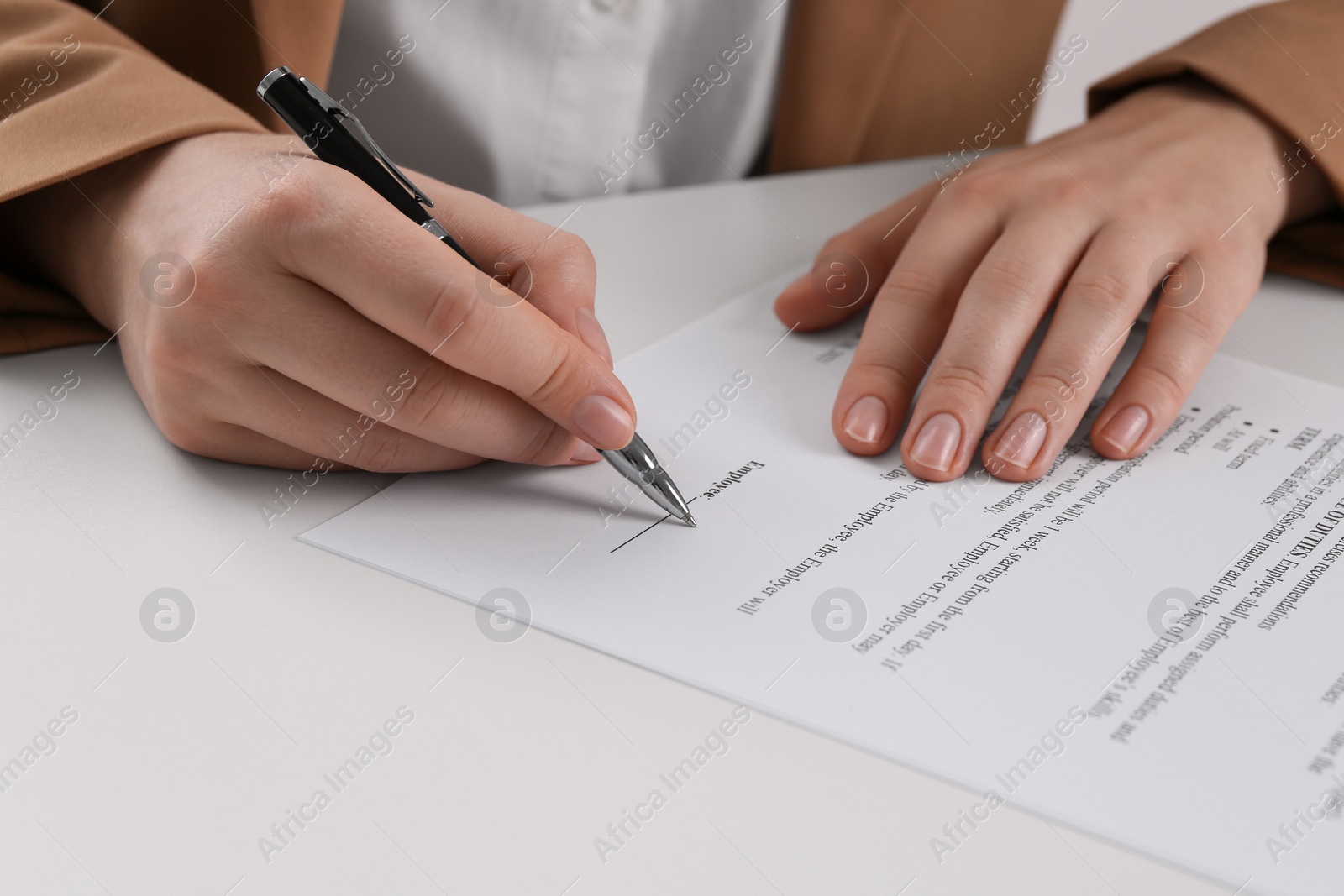 Photo of Businesswoman signing contract at white table, closeup of hands