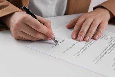 Businesswoman signing contract at white table, closeup of hands