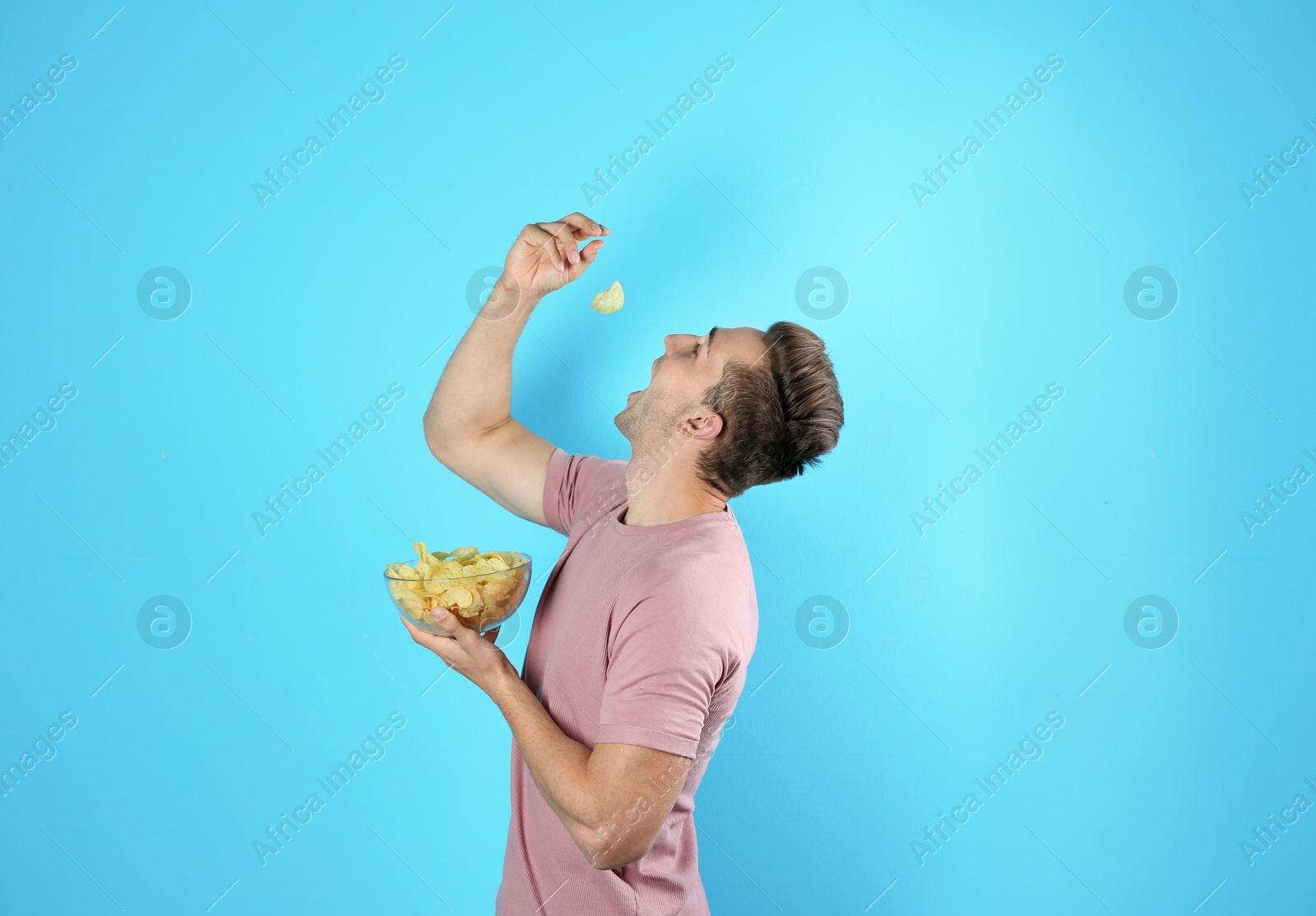 Photo of Man eating potato chips on color background