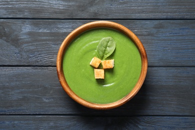 Fresh vegetable detox soup made of spinach with croutons in dish on wooden background, top view