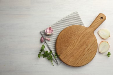 Photo of Cutting board, parsley, garlic and onion on white wooden table, flat lay. Space for text