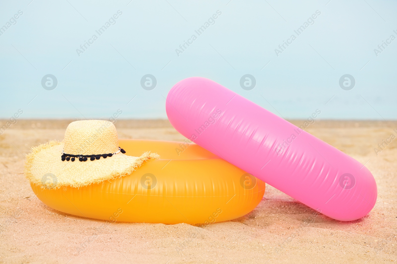 Photo of Colorful inflatable rings and hat on sand. Beach object