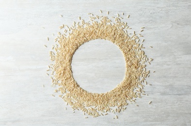 Photo of Round frame made with brown rice on white wooden background, top view. Space for text