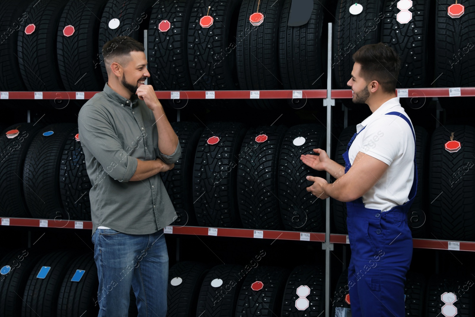 Photo of Mechanic helping client to choose car tire in auto store