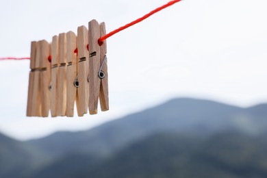 Photo of Wooden clothespins hanging on washing line outdoors