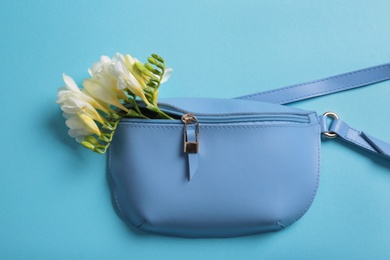 Photo of Flat lay composition with stylish woman's handbag and spring flowers on color background