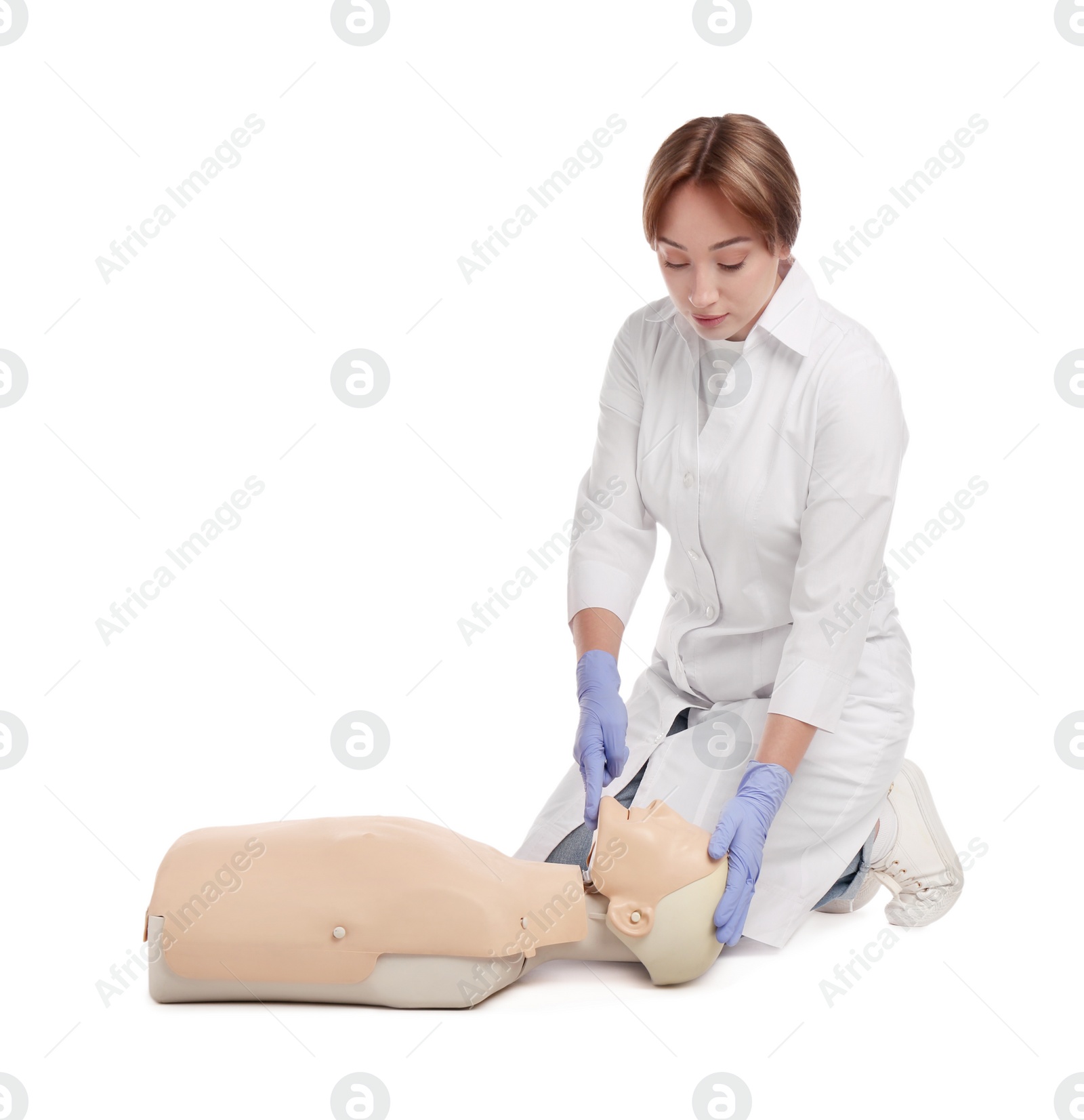 Photo of Doctor in uniform practicing first aid on mannequin against white background