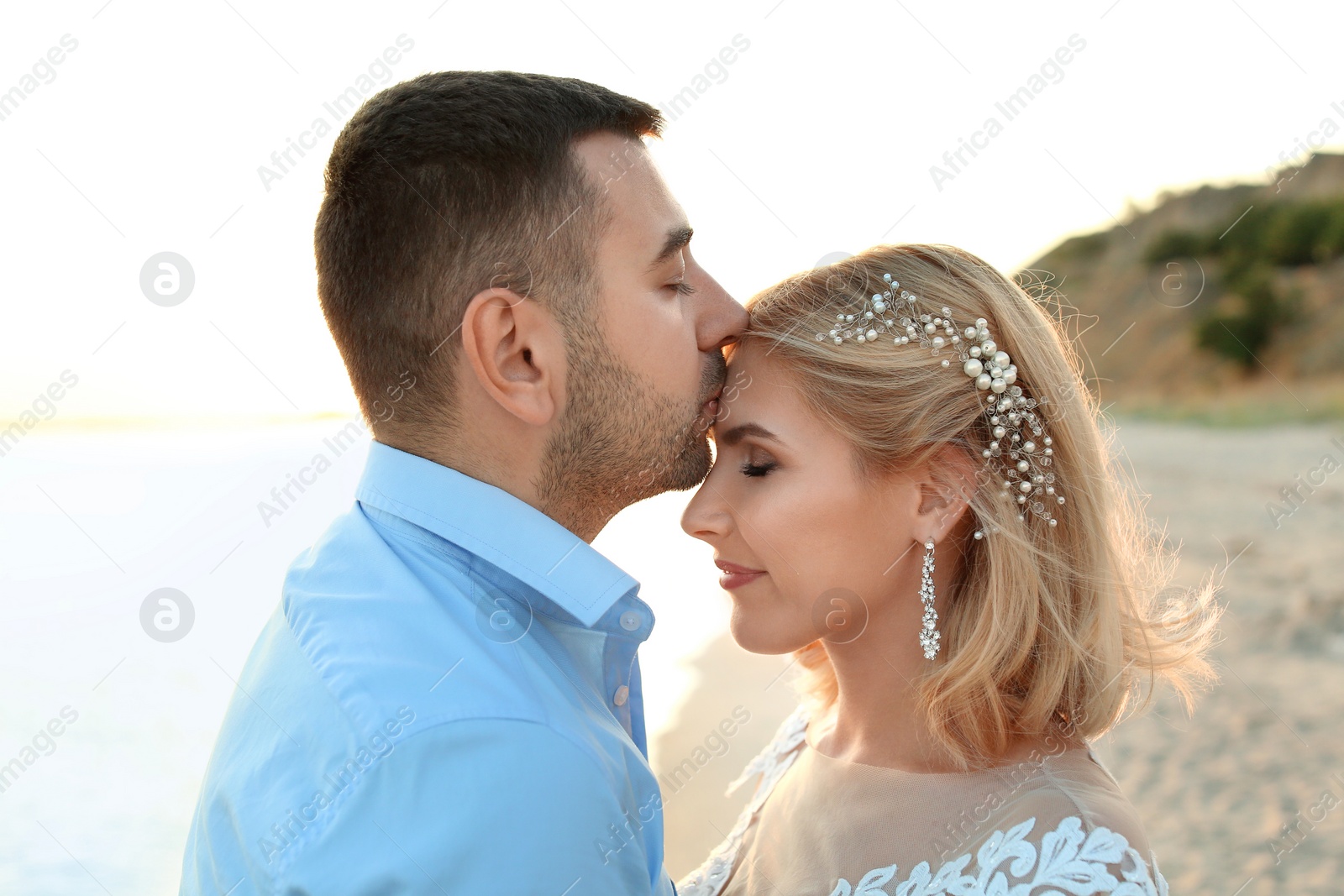 Photo of Wedding couple. Groom kissing bride on beach