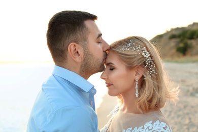 Wedding couple. Groom kissing bride on beach