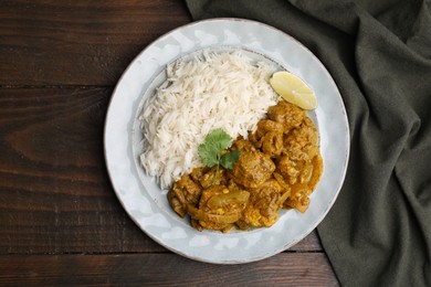 Photo of Delicious chicken curry with rice on wooden table, top view