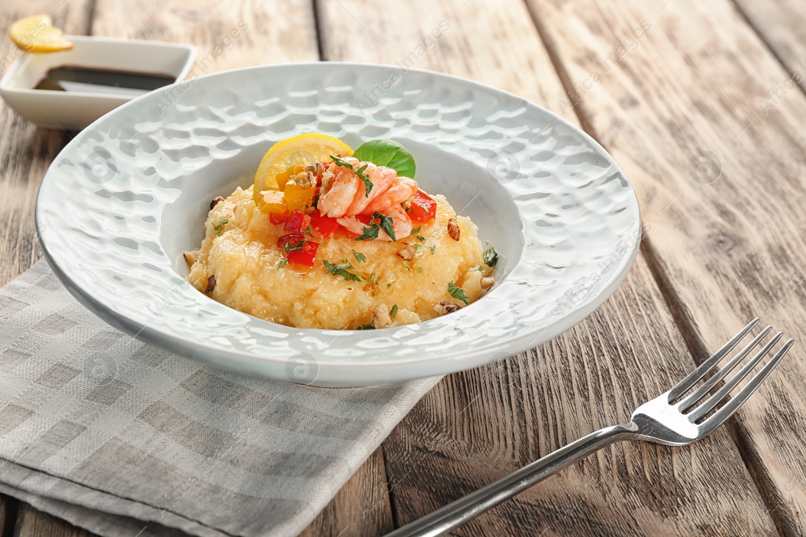 Photo of Plate with tasty shrimps and grits on table