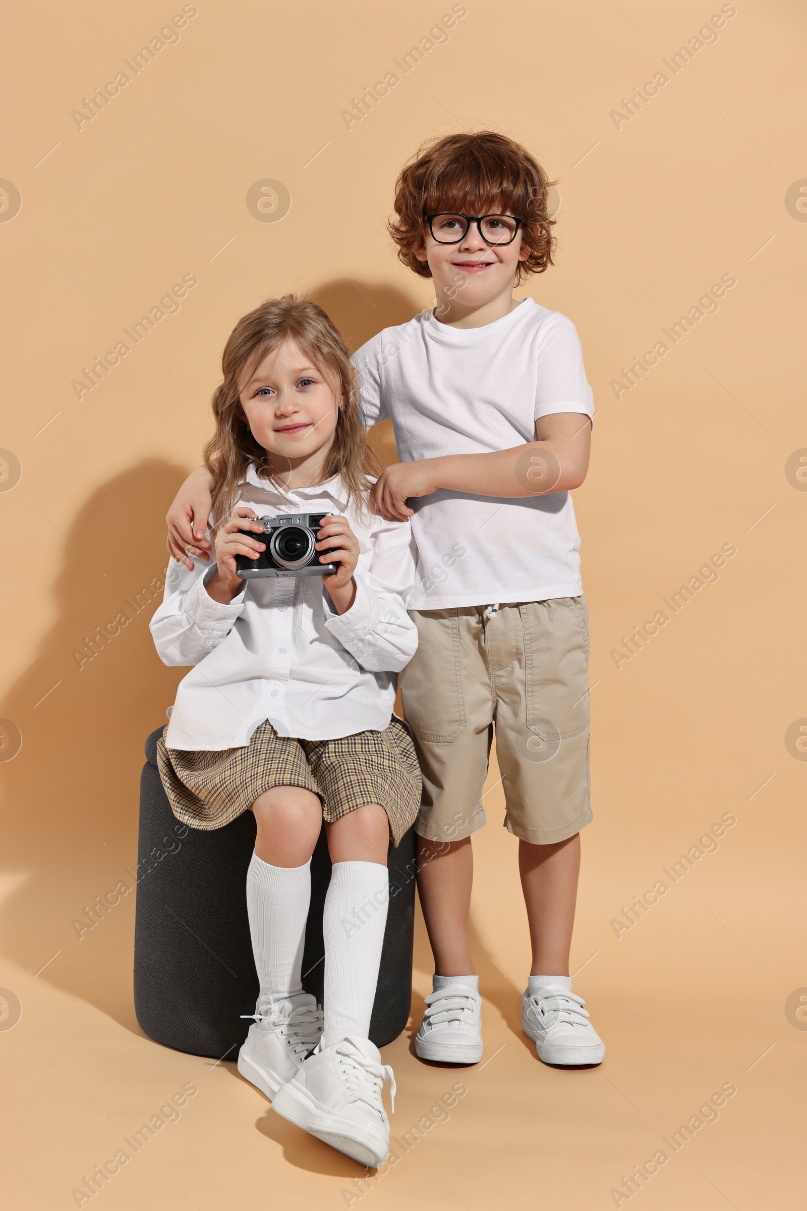 Photo of Fashion concept. Stylish children with vintage camera on pale orange background