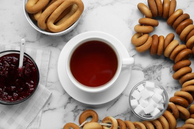 Flat lay composition with delicious ring shaped Sushki (dry bagels) and cup of tea on white marble table