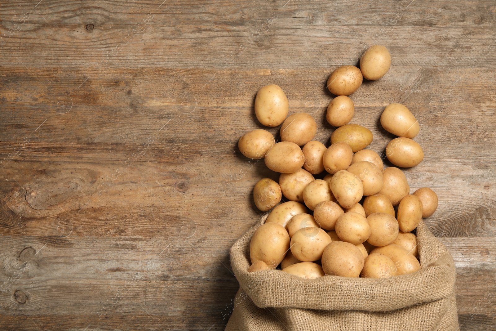 Photo of Raw fresh organic potatoes on wooden background, top view. Space for text