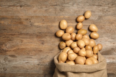 Photo of Raw fresh organic potatoes on wooden background, top view. Space for text