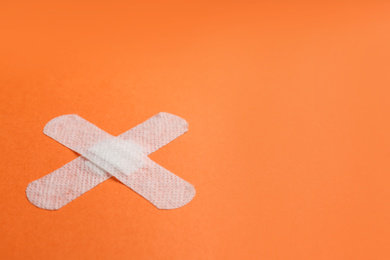 Photo of Sticking plasters on orange background. Space for text