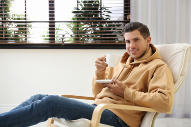 Photo of Attractive man relaxing in armchair near window at home