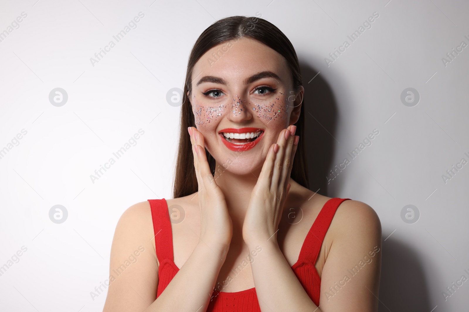 Photo of Happy woman with glitter freckles on light background