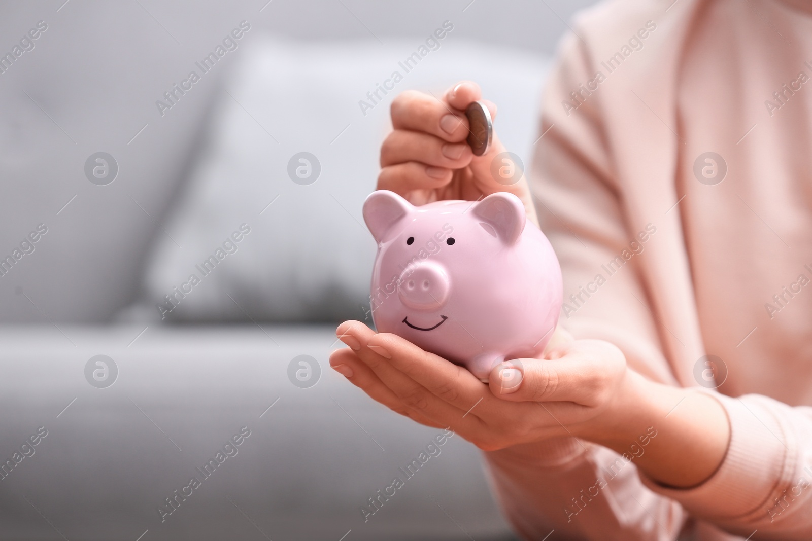 Photo of Woman putting coin into piggy bank at home, closeup. Space for text