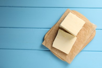 Block of tasty butter on light blue wooden table, top view. Space for text