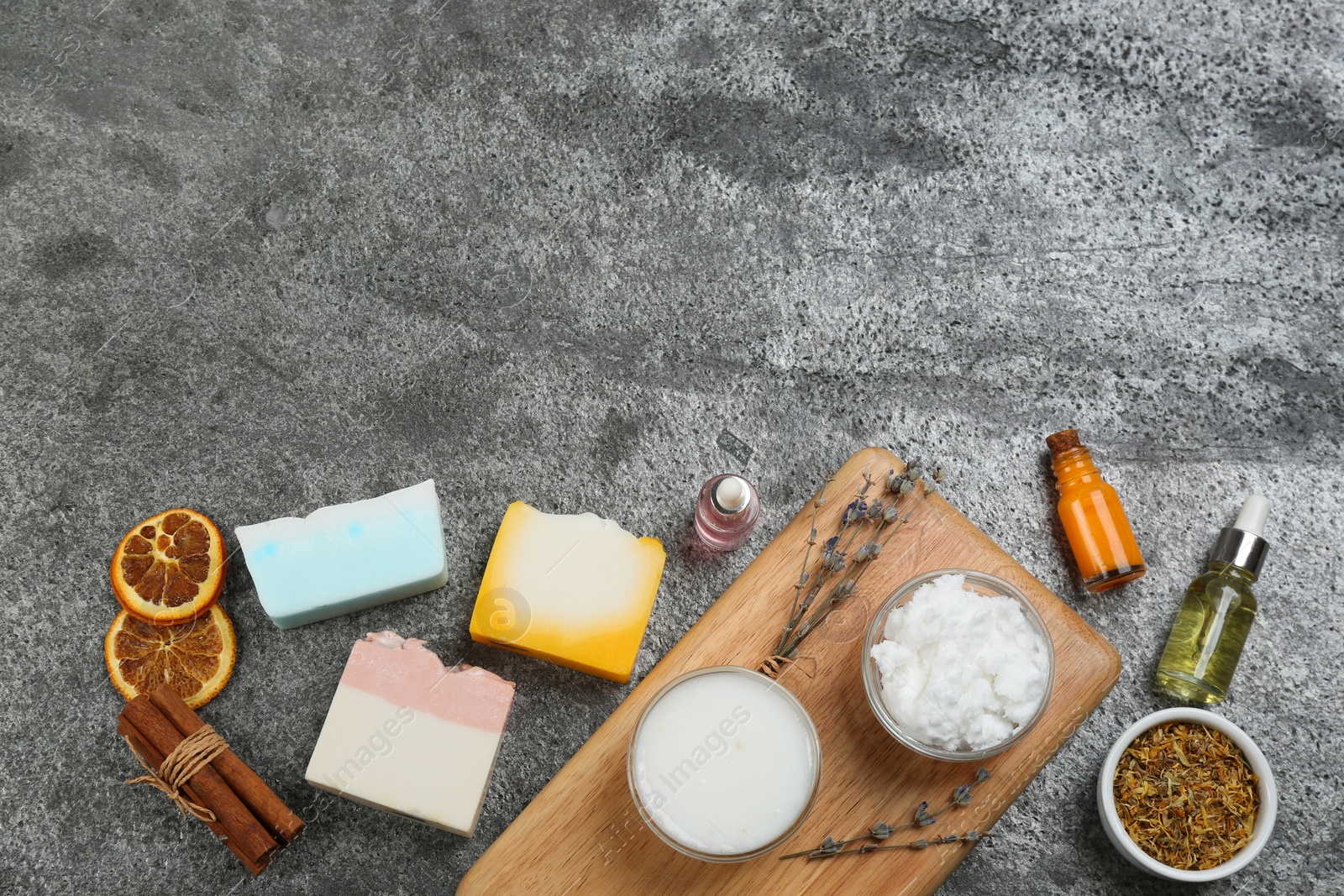 Photo of Flat lay composition with natural handmade soap and ingredients on grey stone table, space for text