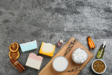 Photo of Flat lay composition with natural handmade soap and ingredients on grey stone table, space for text