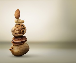 Image of Stacked different nuts on light greyish brown gradient background, space for text