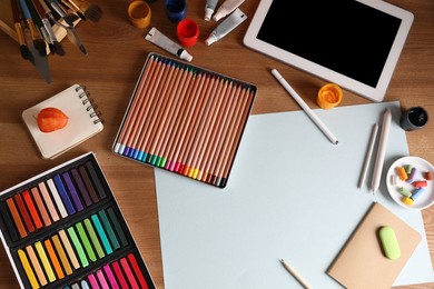 Photo of Artist's workplace with tablet, soft pastels and drawing pencils on table, flat lay