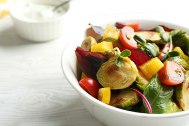 Photo of Delicious salad with roasted Brussels sprouts on white wooden table, closeup