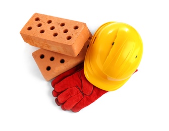 Photo of Hard hat, gloves and bricks on white background, top view. Construction industry