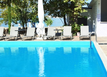 View of outdoor swimming pool with chaise longues