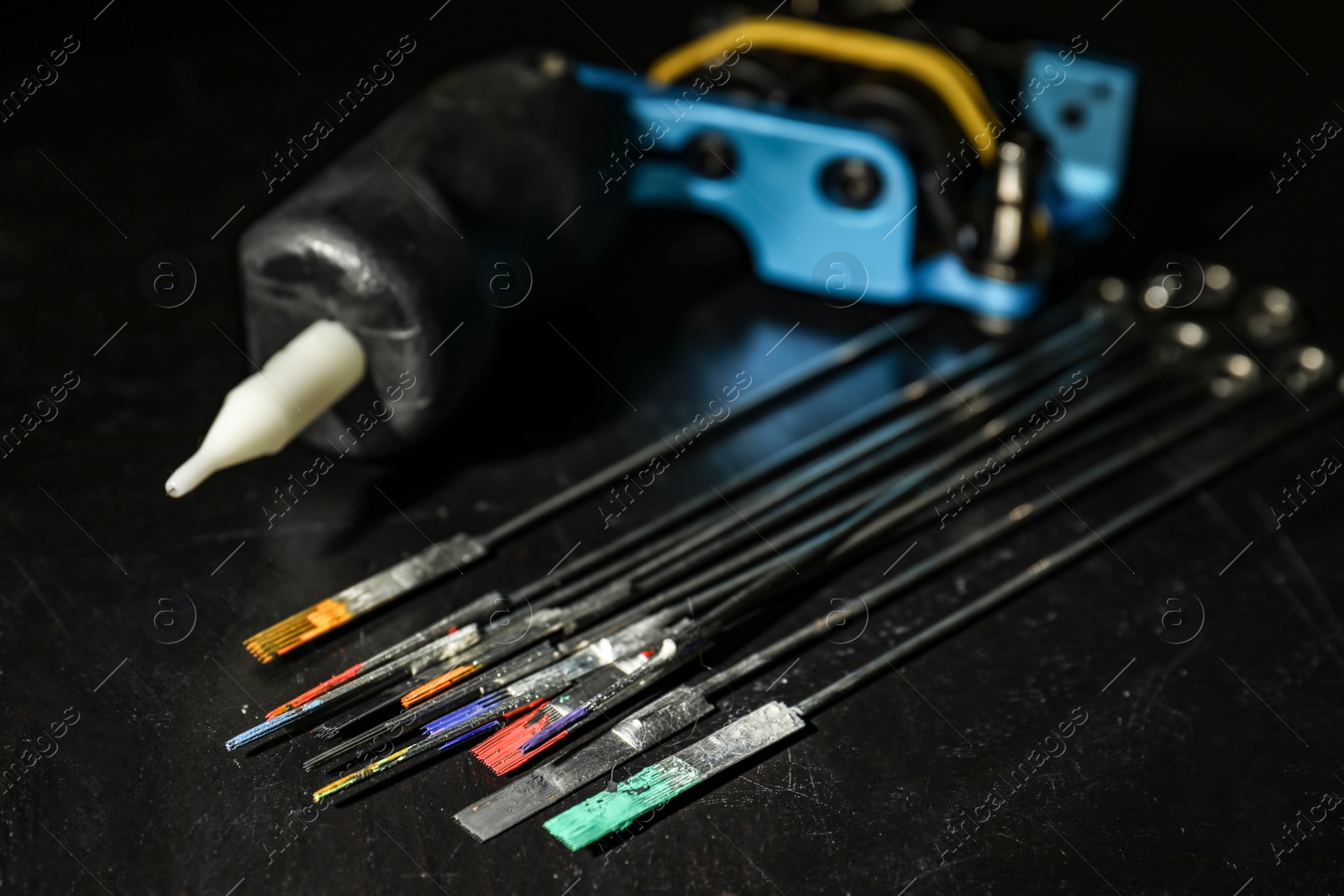 Photo of Tattoo needles covered with colorful inks on black background