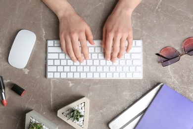 Photo of Woman using keyboard at marble table, top view