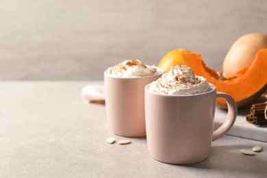 Photo of Cups with tasty pumpkin spice latte on gray table. Space for text