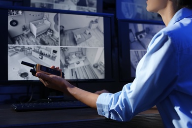 Photo of Female security guard with portable transmitter monitoring modern CCTV cameras indoors, closeup