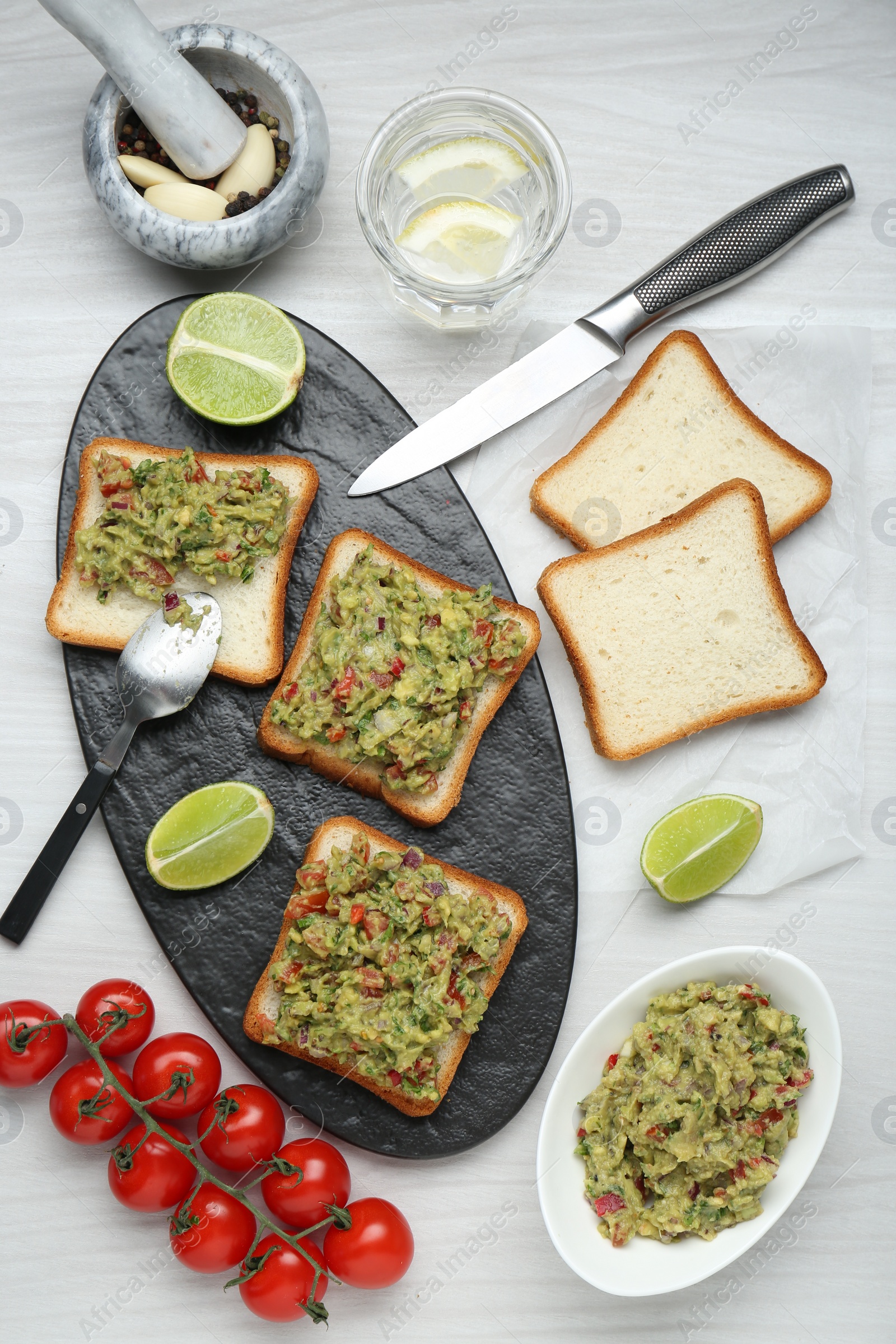 Photo of Delicious sandwiches with guacamole and ingredients on white wooden table, flat lay