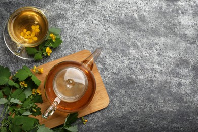 Photo of Aromatic celandine tea and flowers on grey table, flat lay. Space for text