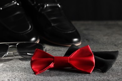 Stylish red and black bow ties, sunglasses and shoes on gray background