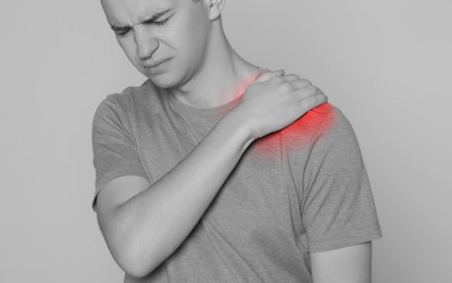 Image of Man suffering from pain in shoulder, closeup. Black and white effect