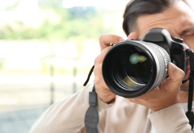 Photo of Male photographer with professional camera on blurred background. Space for text