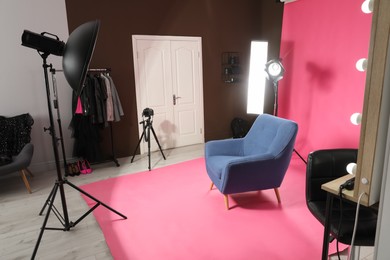 Photo of Stylish blue armchair in photo studio with professional equipment