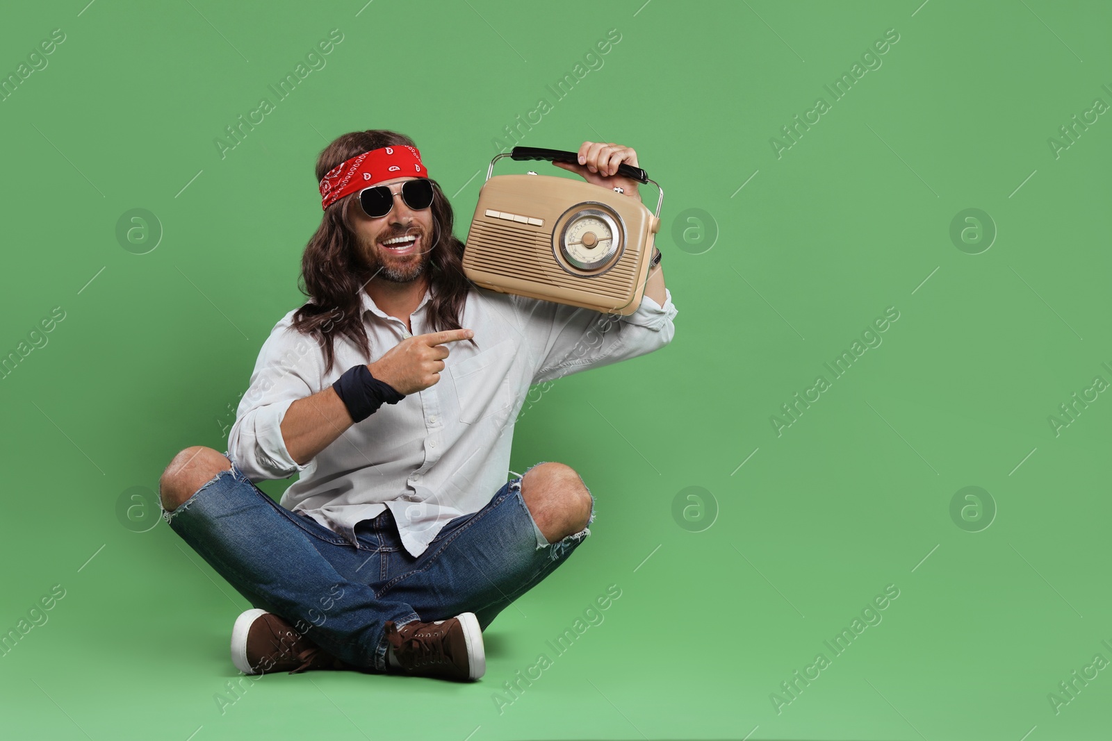 Photo of Stylish hippie man in sunglasses with retro radio receiver on green background