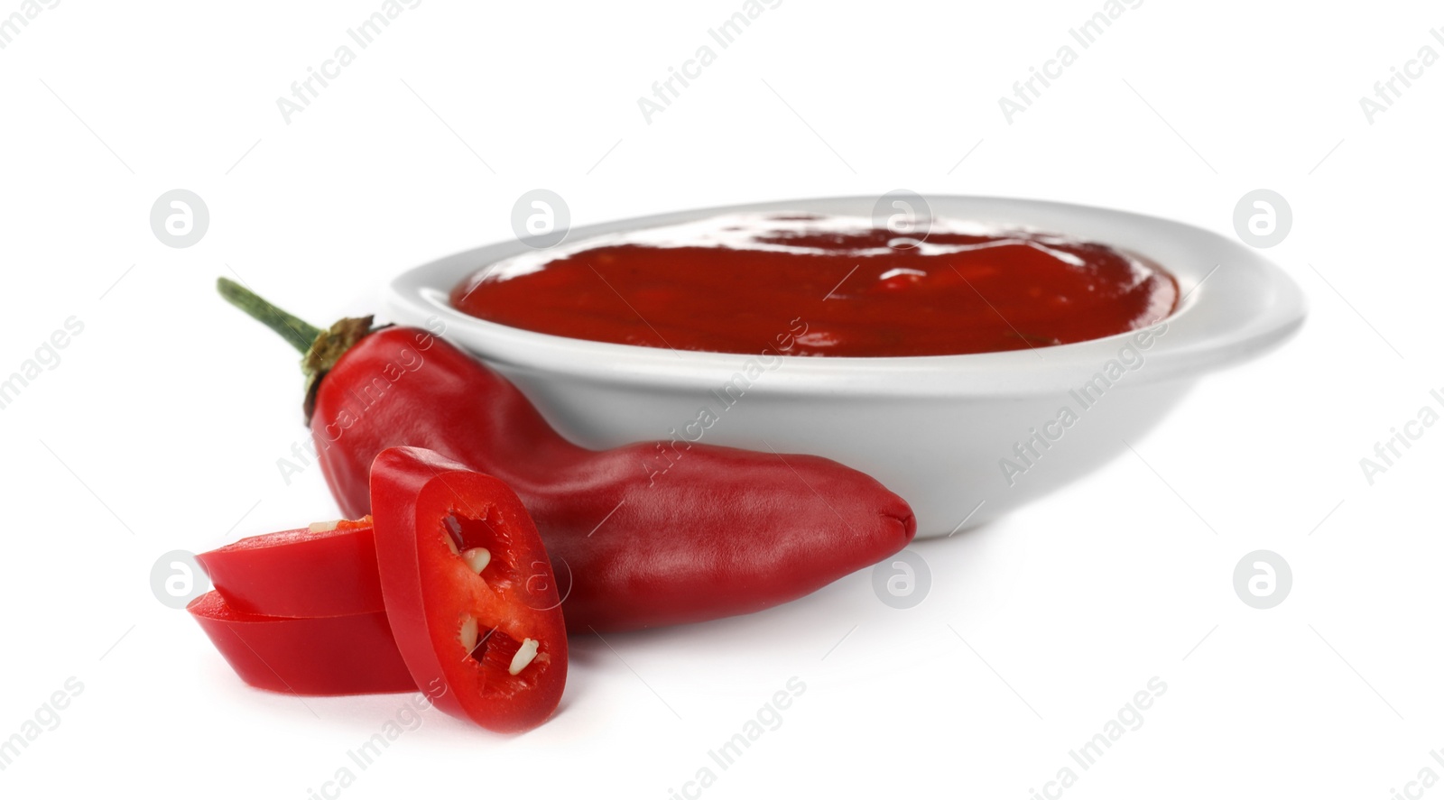 Photo of Bowl with spicy chili sauce and fresh pepper on white background