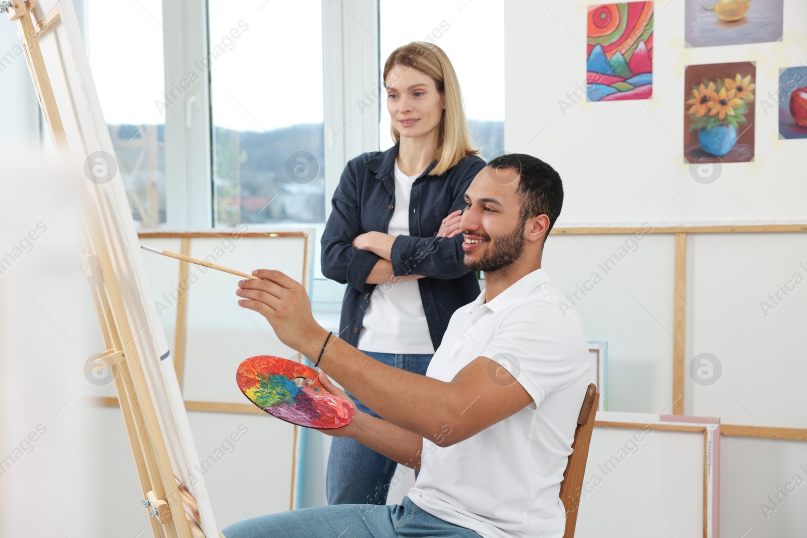 Photo of Artist teaching her student to paint in studio. Creative hobby