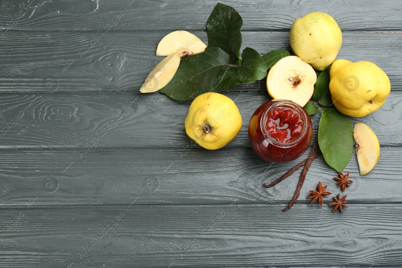 Photo of Delicious quince jam and fruits on grey wooden table, above view. Space for text