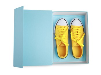 Photo of Pair of stylish yellow shoes in turquoise box on white background, top view