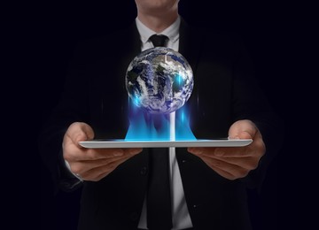 Image of Internet technology concept. Man holding tablet and virtual icon of Earth on dark background