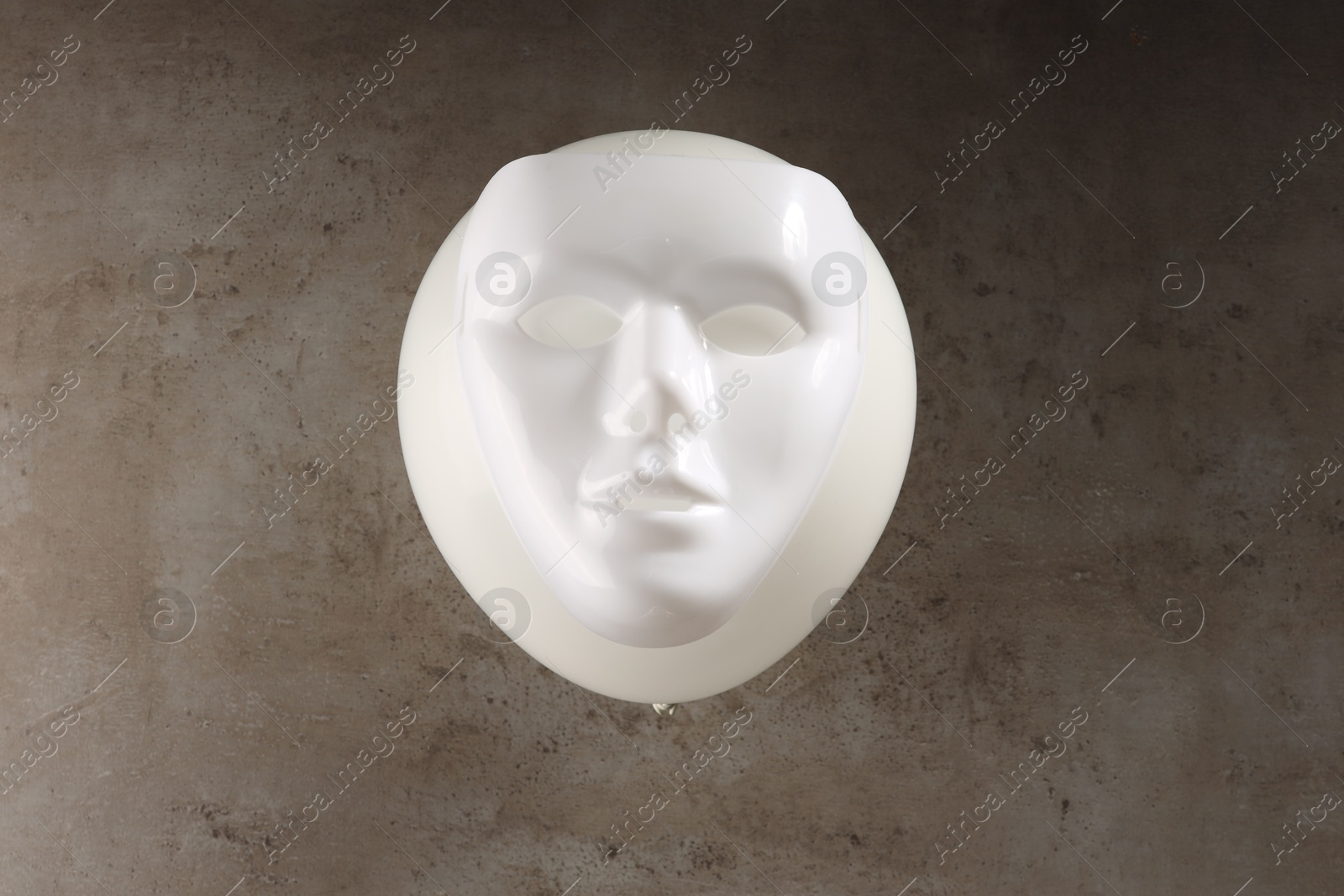 Photo of Theatrical performance. Plastic mask and white balloon on grey table, top view