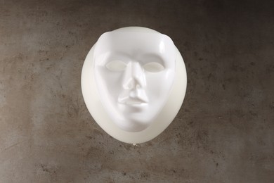 Theatrical performance. Plastic mask and white balloon on grey table, top view