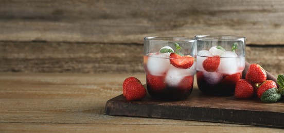 Photo of Delicious cocktails with strawberries, mint and ice balls on wooden table, space for text